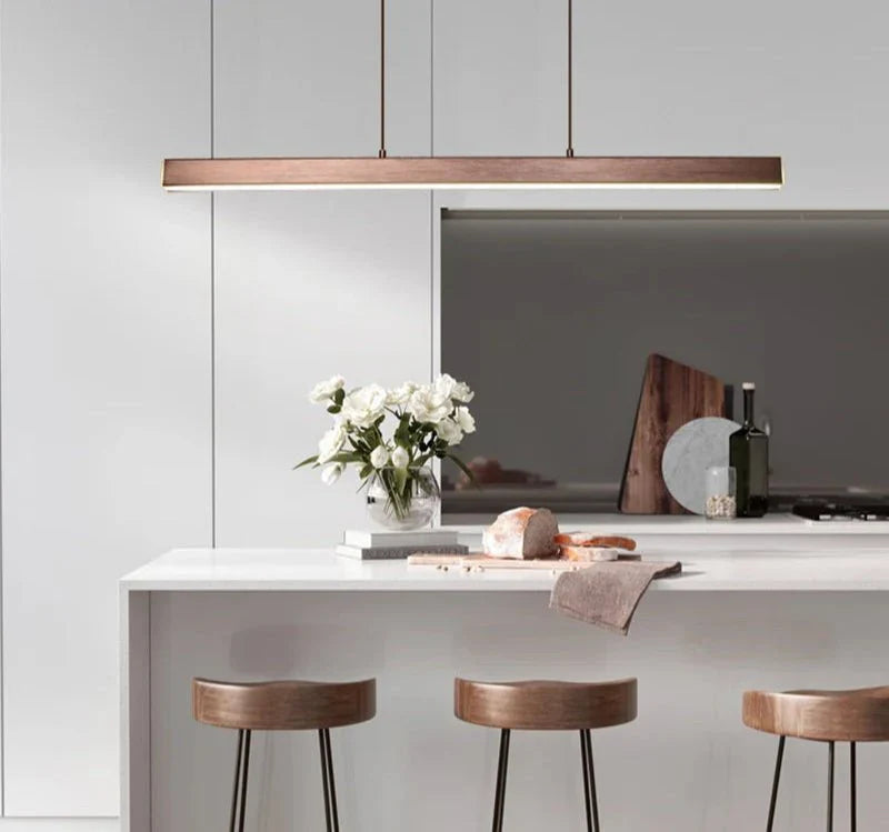 Minimal suspended pendant light illuminating a modern kitchen island.