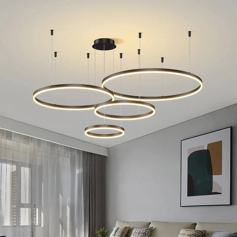 Modern LED pendant ceiling light fixture in brushed gold finish, featuring multiple circular rings hanging at varying heights, illuminating a contemporary living room.