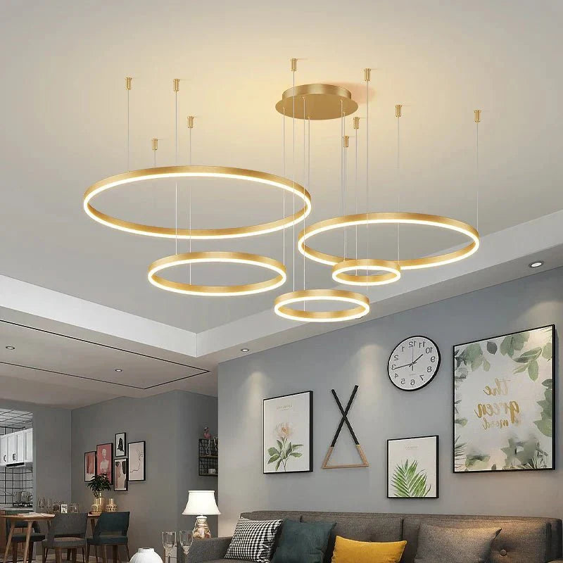 Modern LED pendant ceiling light fixture with gold rings in a stylish living room setting.