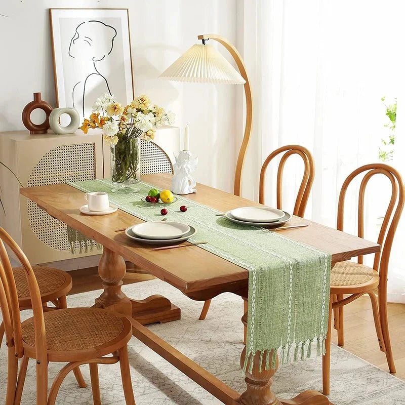 Woven natural cotton table runner on dining table with rustic design and macrame embroidery, adding a boho feel.