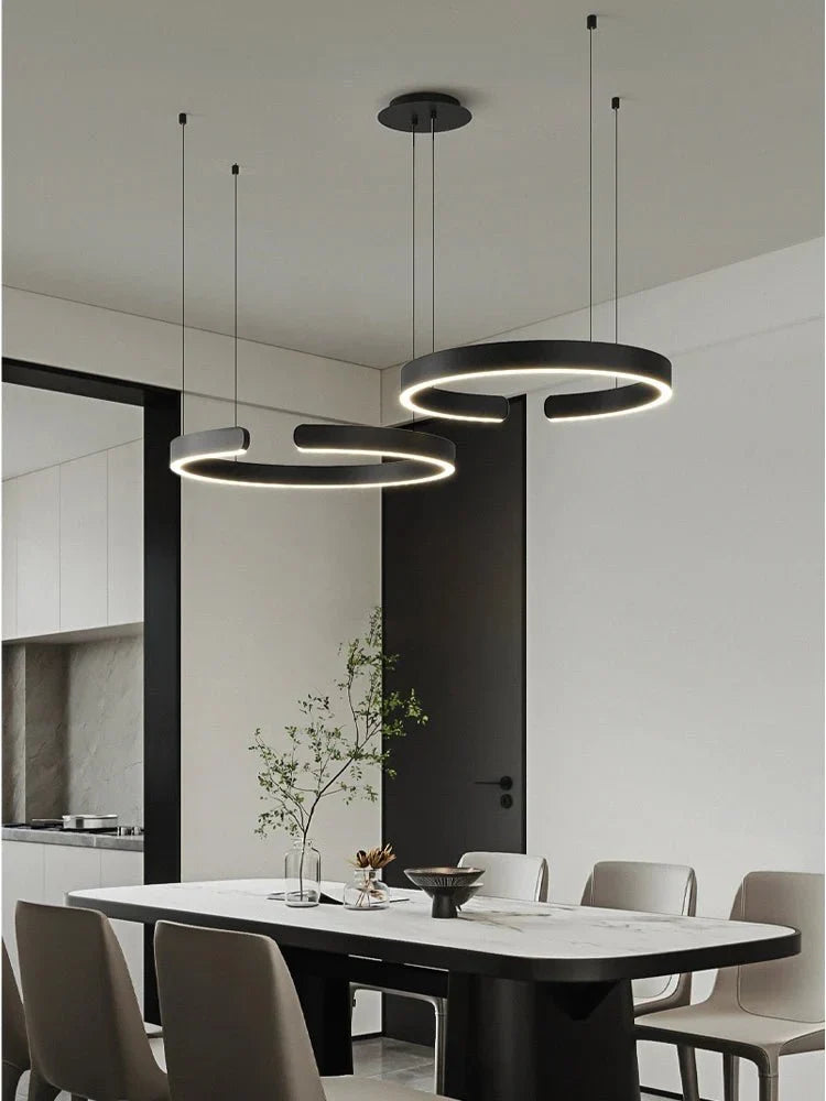 Minimalist geometric LED pendant lights hanging over a modern dining table.