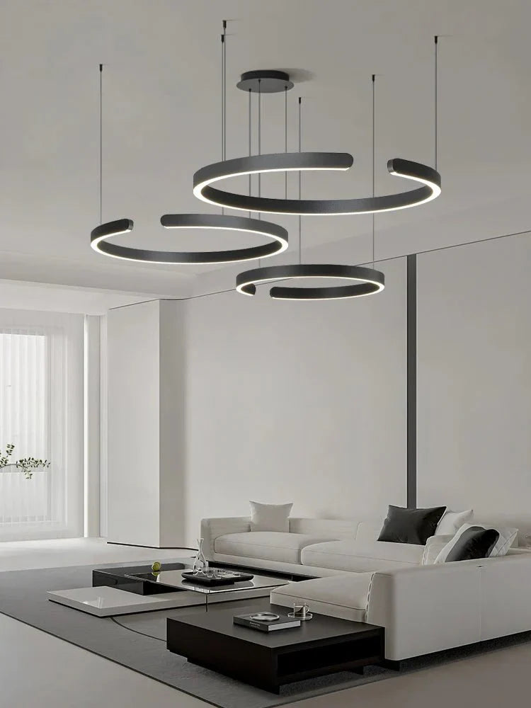 Minimalist black and white geometric LED pendant light illuminating a modern living room.