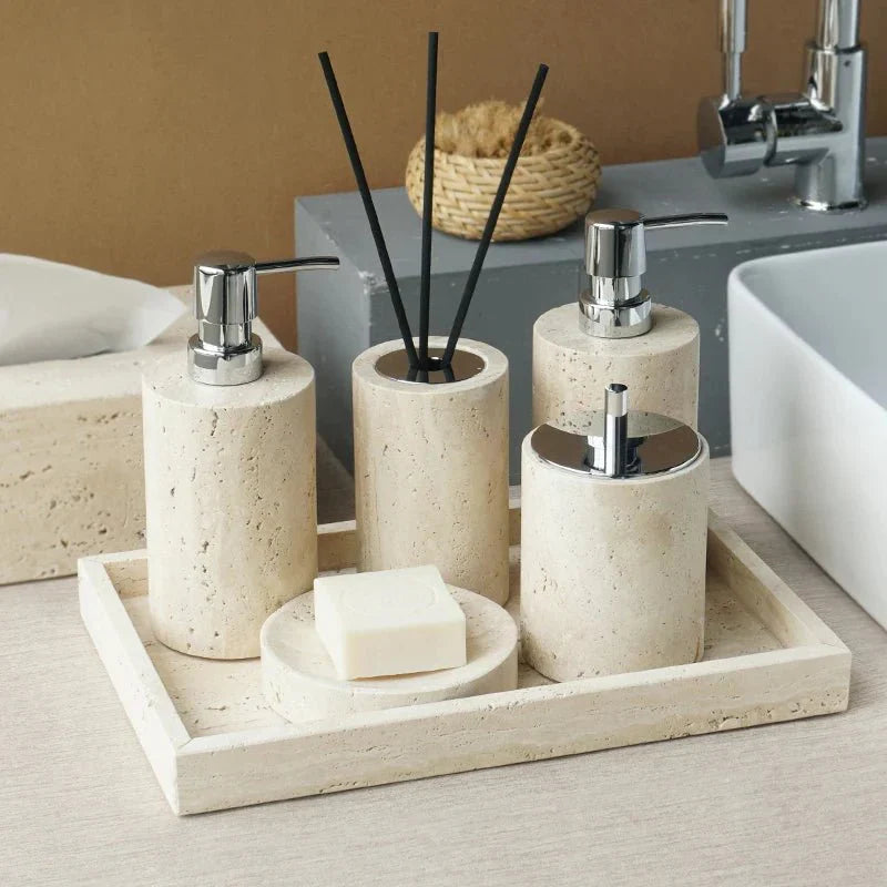 Minimalist travertine bathroom set with dispensers and holder on a countertop.