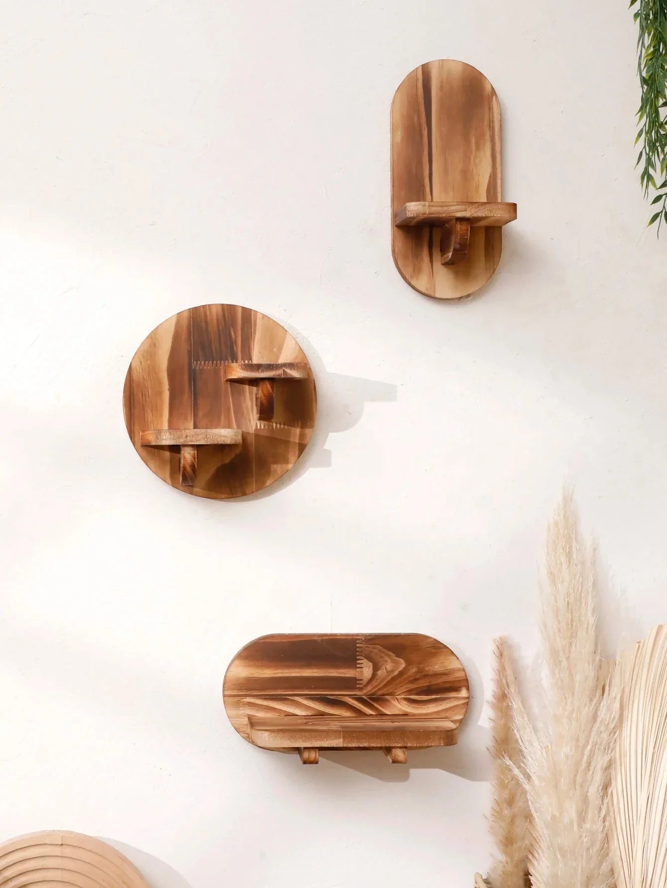 Oval and round wooden wall shelves set displaying artifacts on a white wall, featuring a natural, warm finish.
