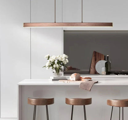 Minimal suspended pendant light illuminating a modern kitchen island.