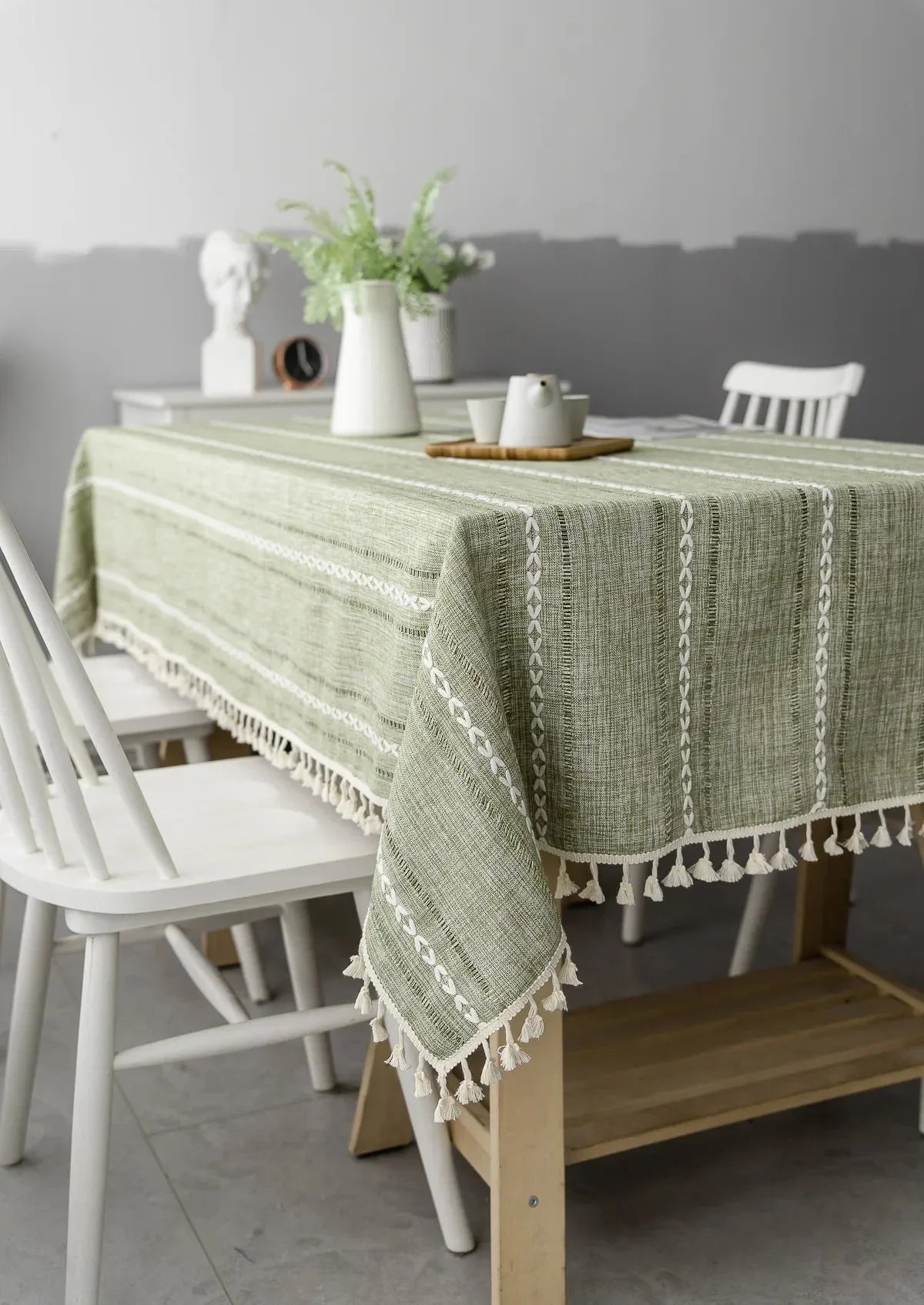 Soft linen-feel green tablecloth with woven pattern and tassel edge on dining table.