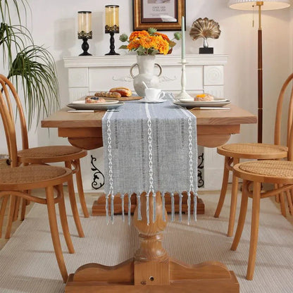 Woven natural cotton table runner with rustic design and macrame embroidery on wooden dining table.