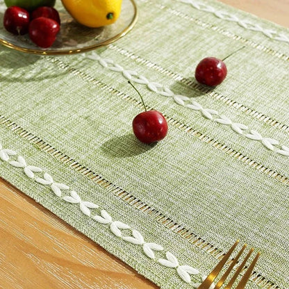 Woven natural cotton table runner with rustic design and embroidery detailing on dining table.