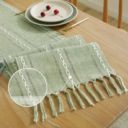 Woven natural cotton table runner with macrame embroidery and tassels on a dining table.