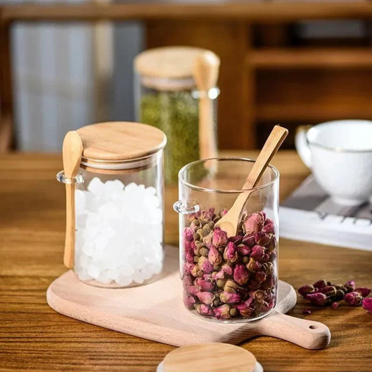Airtight glass spice jars with bamboo lids and spoons on a wooden table.
