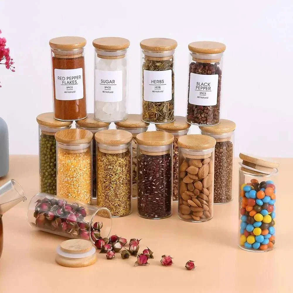 Glass spice jars with bamboo lids in a kitchen setting, showcasing a variety of herbs and spices in an organized display.