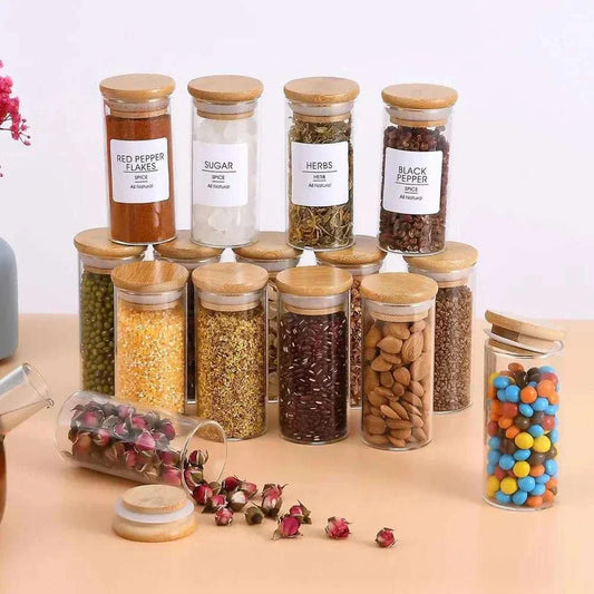 Glass spice jars with bamboo lids in a kitchen setting, showcasing a variety of herbs and spices in an organized display.