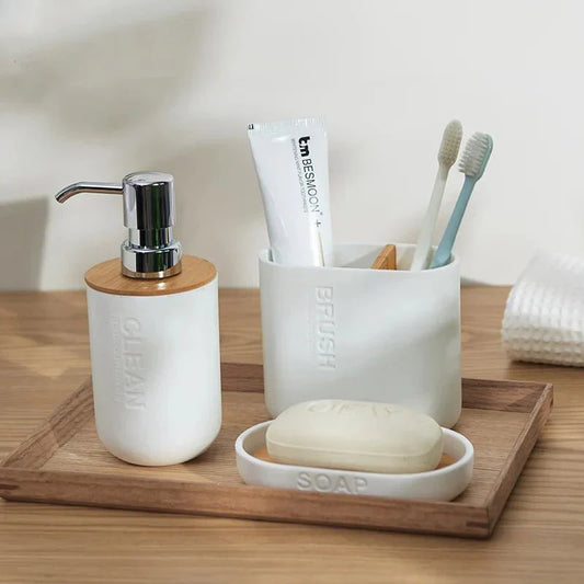 Minimalist natural bamboo bathroom set including ceramic dispensers and soap holder on a wooden tray.