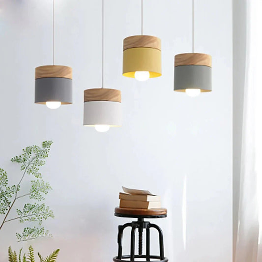 Modern LUMINOT™ pendant light with natural wood and matte color finish, illuminating a living room setting.