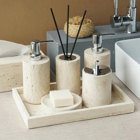 Minimalist travertine bathroom set with dispensers and holder on a countertop.