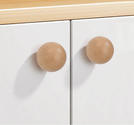 Natural wood knob on a white cabinet drawer for minimalist design.