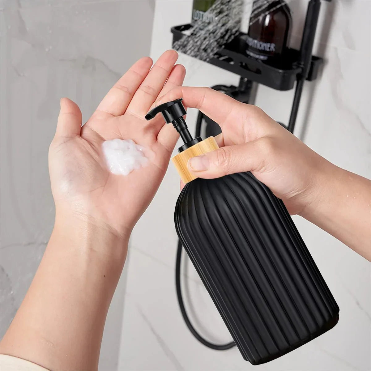 RIGO™ bathroom dispenser in ribbed matte black with bamboo top, shown dispensing soap into a hand.