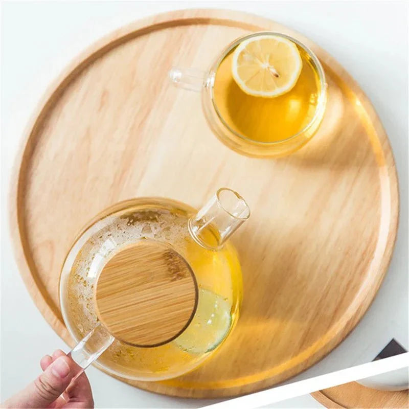 Round wooden serving tray with a teapot and lemon tea cup.