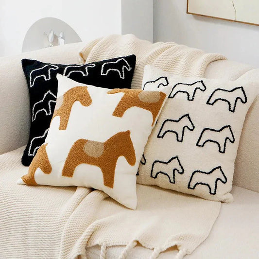 Embroidered pillow covers on a sofa with abstract animal motifs.